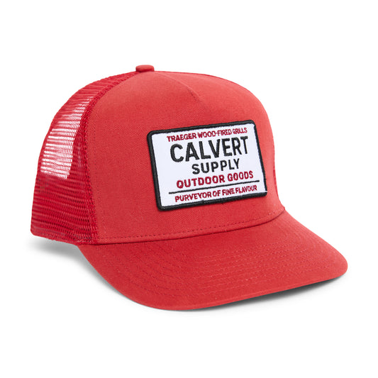Red cap with a Calvert Supply Outdoor Goods patch and traeger grills on a white background