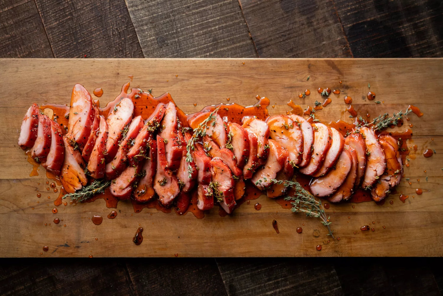 Sliced cured meat with herbs on a wooden cutting board